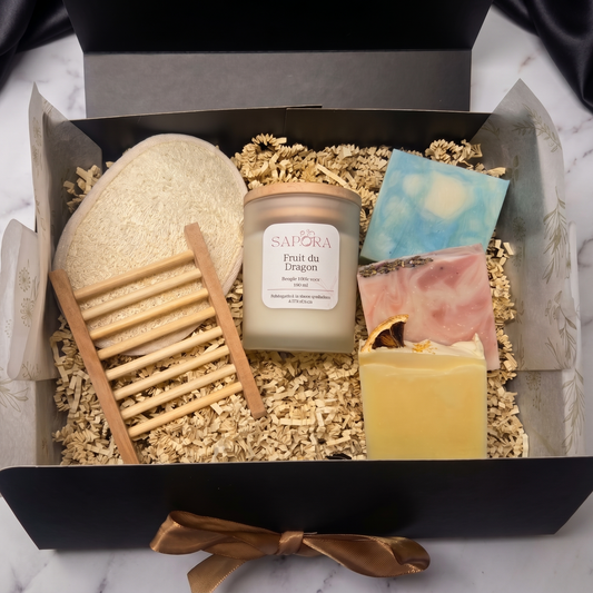 Coffret cadeau bien-être Sapora comprenant trois savons artisanaux, une bougie de soya naturelle, un porte-savon en bois et une éponge luffa sur fond épuré.