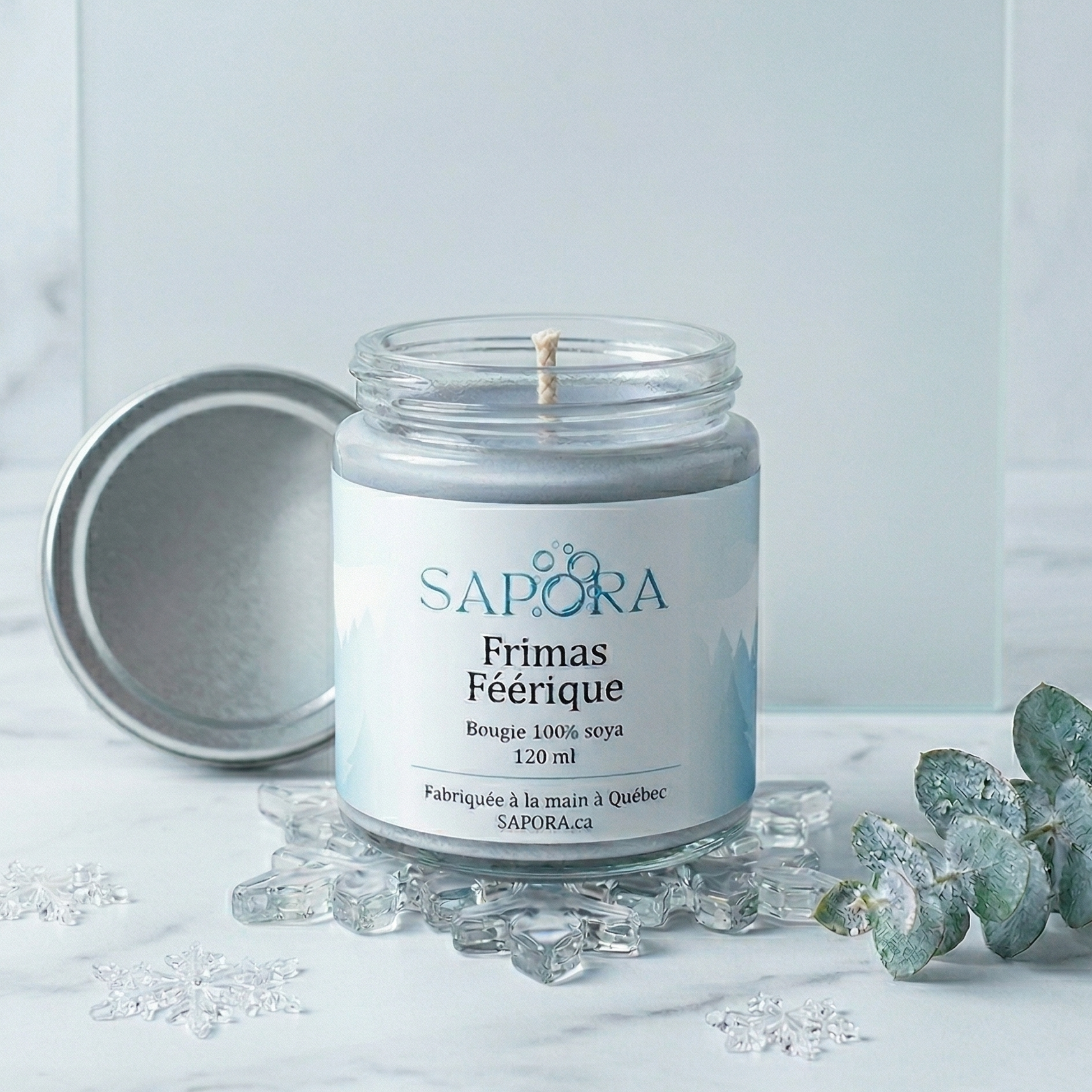 Bougie de soya Sapora Frimas Féérique dans un décor de Noël doux avec grenades fraîches, mûres et branches de conifères sur une table en bois d'acajou.