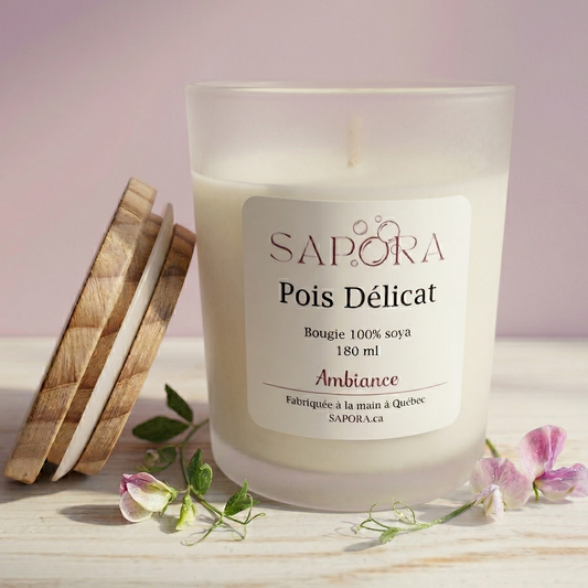 Bougie de soya Sapora Pois Délicat dans un pot en verre givré avec son couvercle en bois et des fleurs de pois de senteur sur une surface claire.