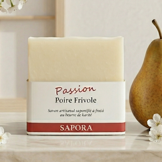 Savon artisanal Sapora Poire Frivole au beurre de karité, présenté sur un marbre blanc avec une poire fraîche et des fleurs de poirier dans un décor zen épuré.