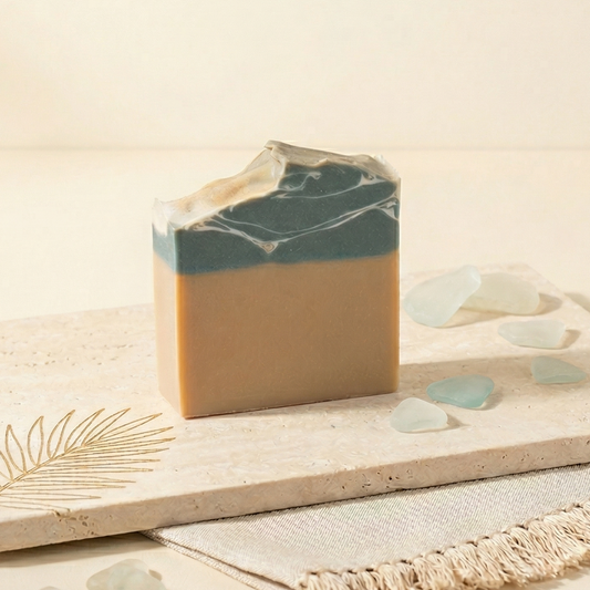 Savon artisanal "Soleil des Caraïbes" de Sapora à l'huile d'amande douce, posé sur un socle en pierre naturelle avec décor minimaliste et épuré.