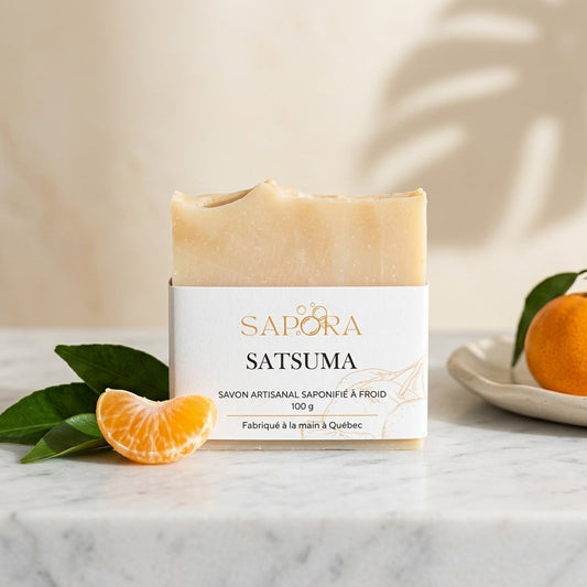 Savon artisanal Sapora au parfum de satsuma saponifié à froid posé sur un comptoir en marbre avec des mandarines fraîches et un éclairage naturel.